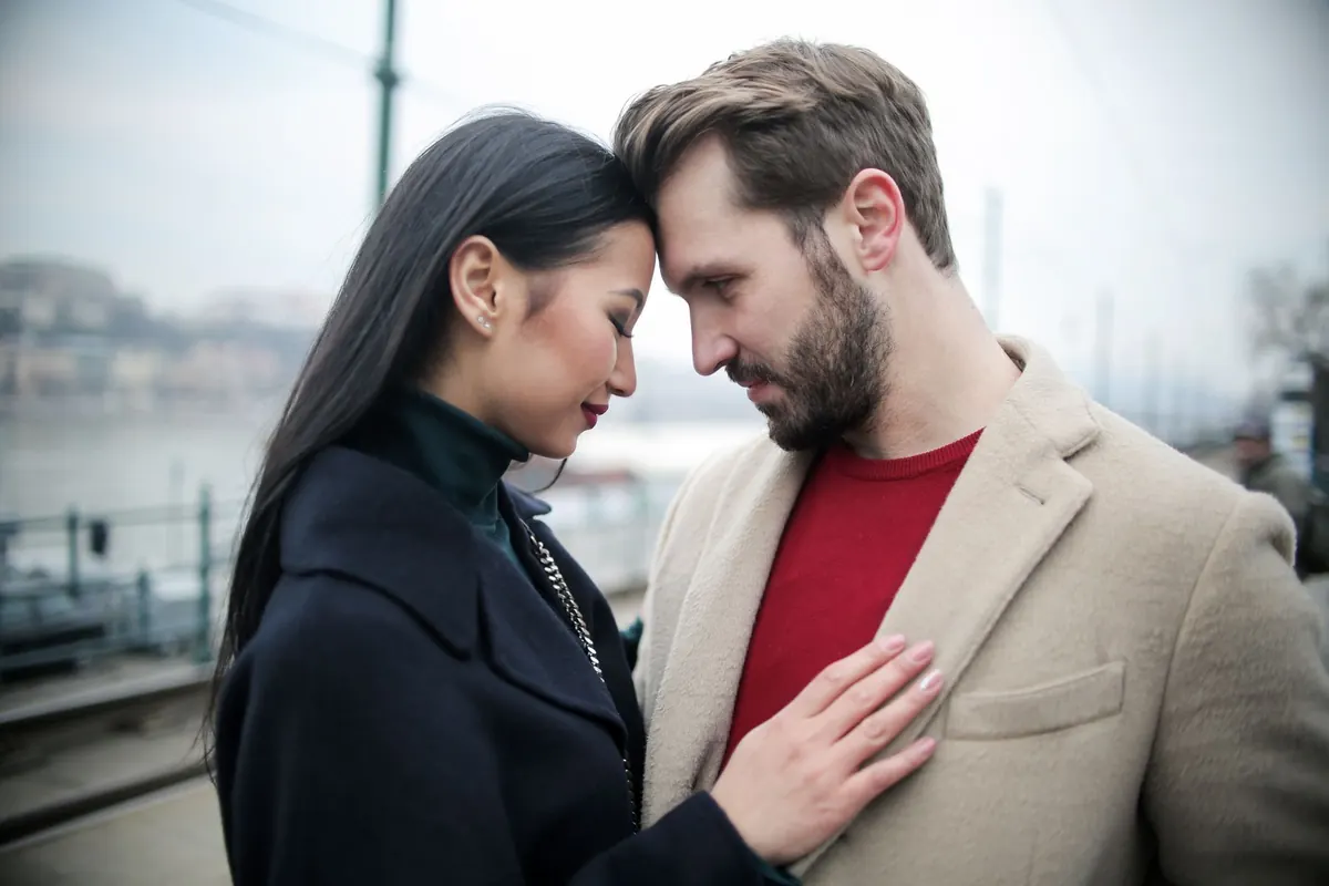 Hai người tựa trán vào nhau bên bờ sông một ngày trời u ám