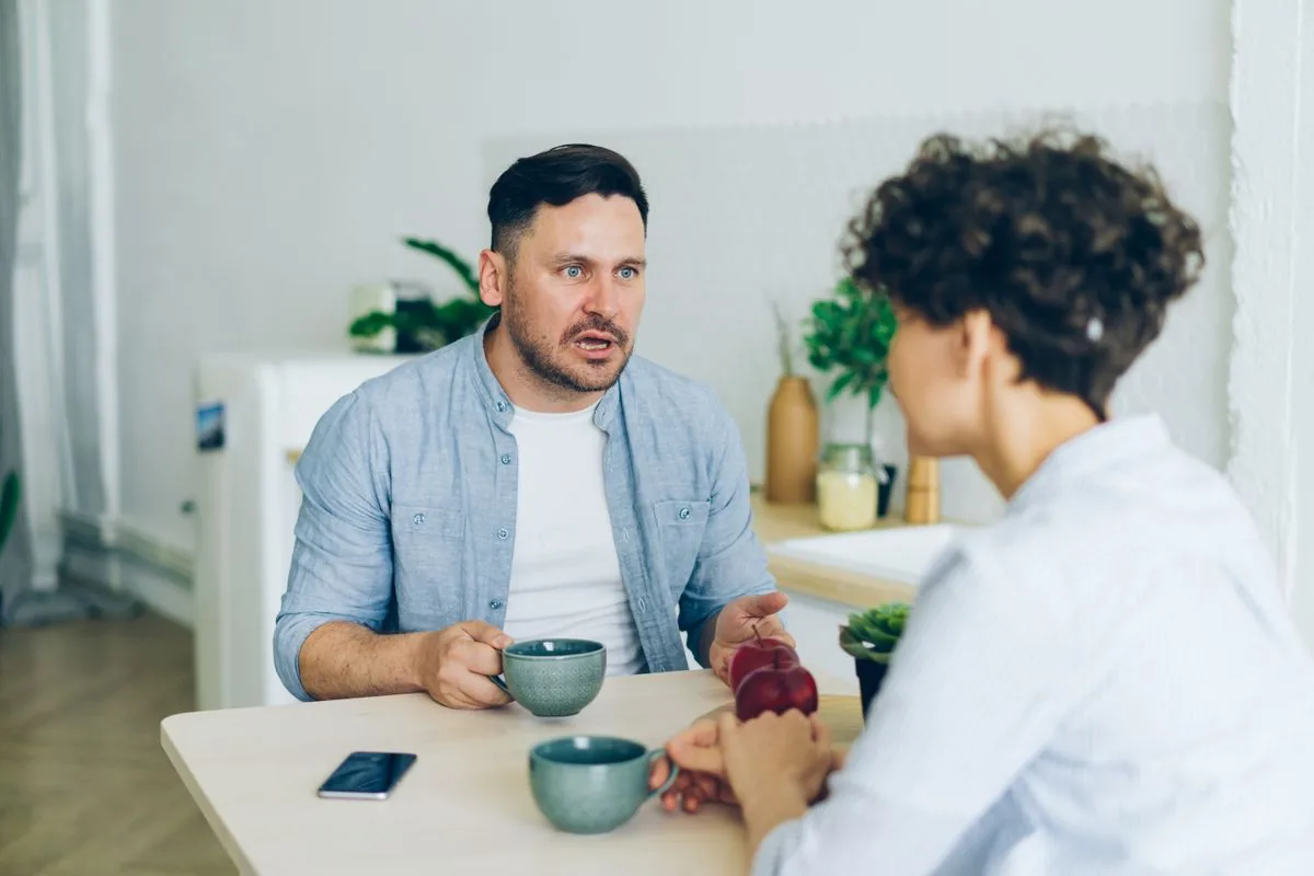 Hai người ngồi nói chuyện nghiêm túc bên bàn bếp
