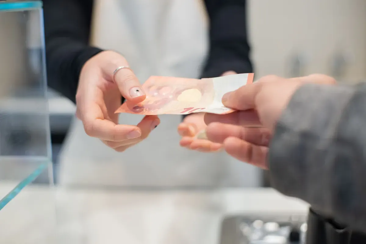 Hai bàn tay trao tiền mặt ở quầy thanh toán quán cà phê