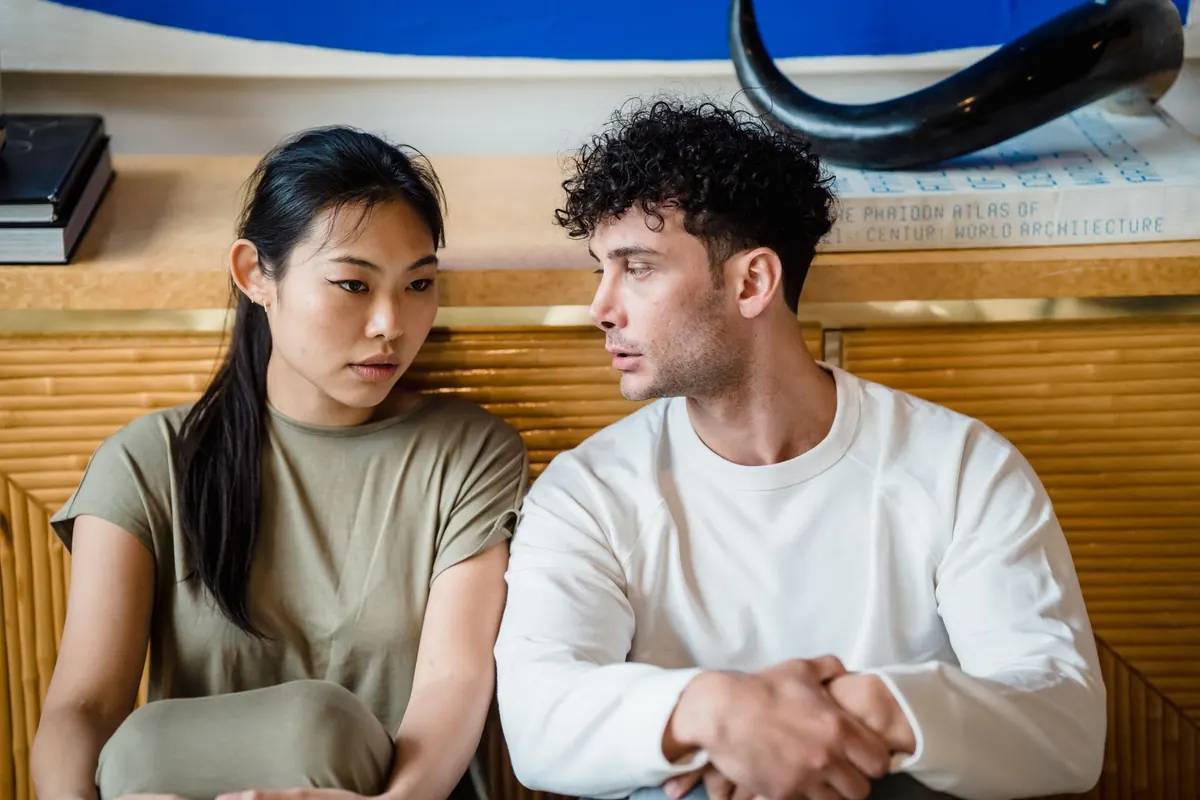 Một cặp đôi ngồi cạnh nhau trên sàn nhà, nói chuyện nghiêm túc