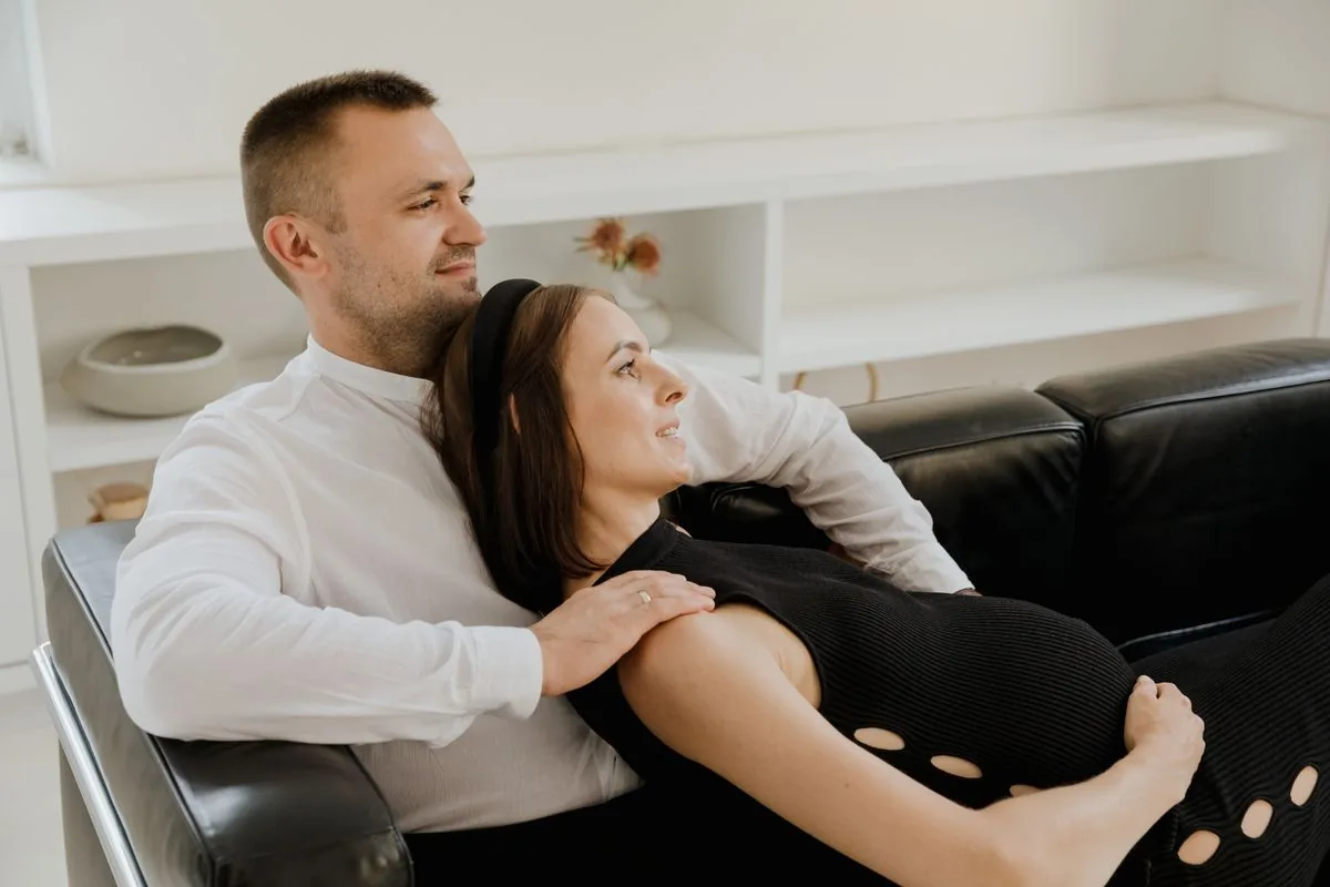Một đôi đang chờ con ngồi cạnh nhau trên ghế sofa