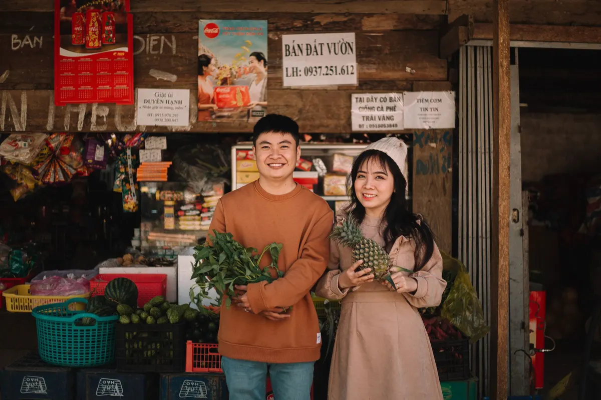 Một đôi đang cầm trái cây và rau tươi ở quầy hàng ngoài chợ
