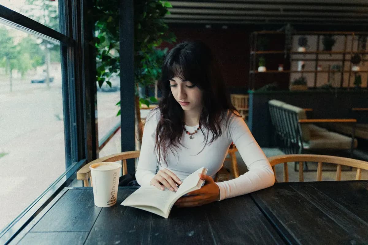 Một người ngồi đọc sách bên tách cà phê trong quán yên tĩnh