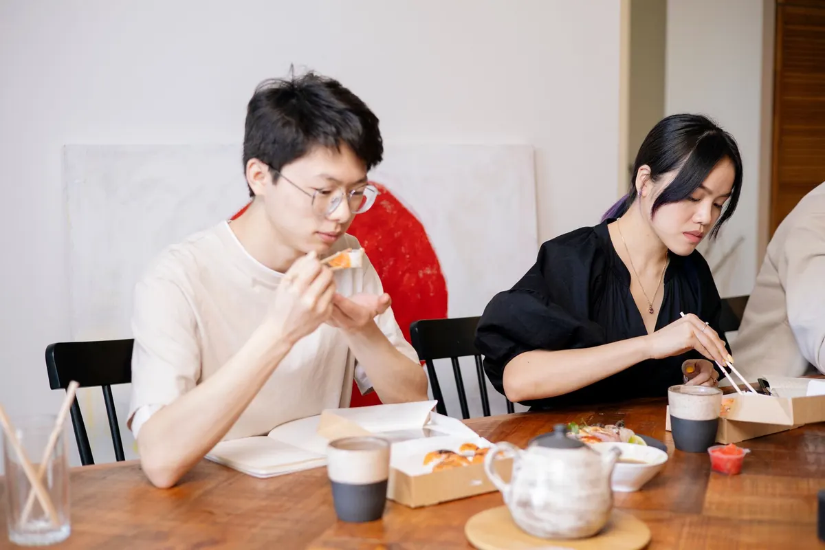 Đôi nam nữ ngồi cạnh nhau bên bàn ăn, mỗi người lặng lẽ với phần ăn của mình