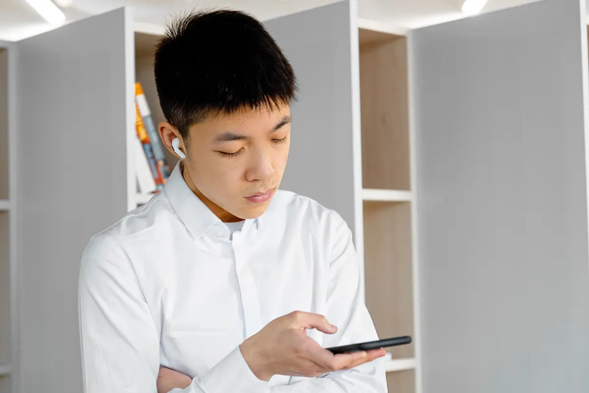 Chàng trai đeo tai nghe nhìn điện thoại với vẻ mặt trầm ngâm